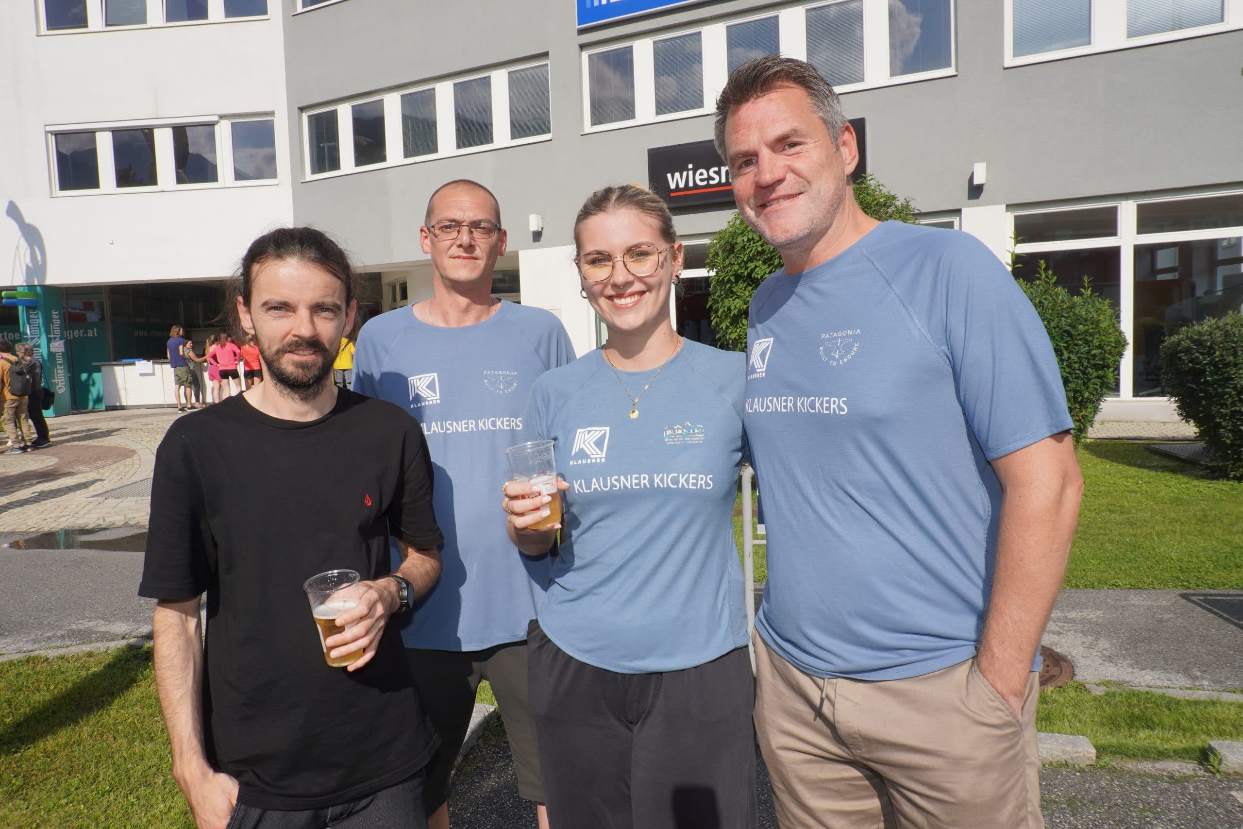 Vier Mitarbeiter der Klausner Kickers, darunter Martin Schiessl, Hannes Überall, Sophia Fahringer und Gregor Novotny, stehen beim TWI Sommerfest in Innsbruck und genießen das Event.