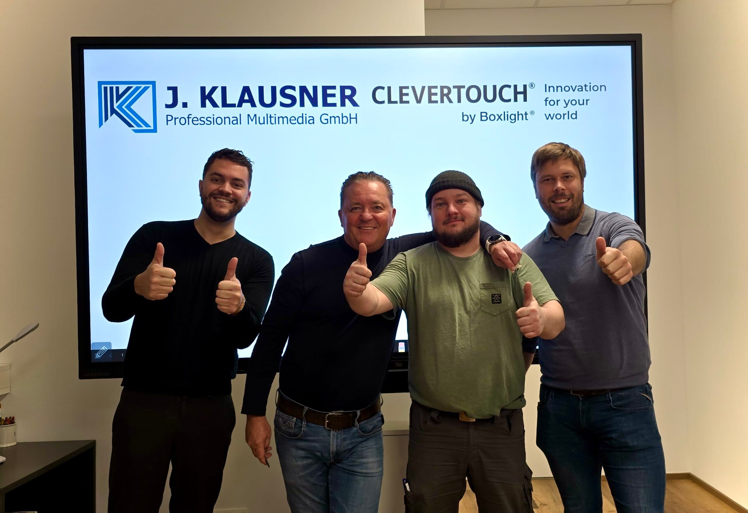 Das Klausner Team steht vor einem interaktiven Multitouch-Display mit dem Klausner-Logo und Clevertouch Logo.